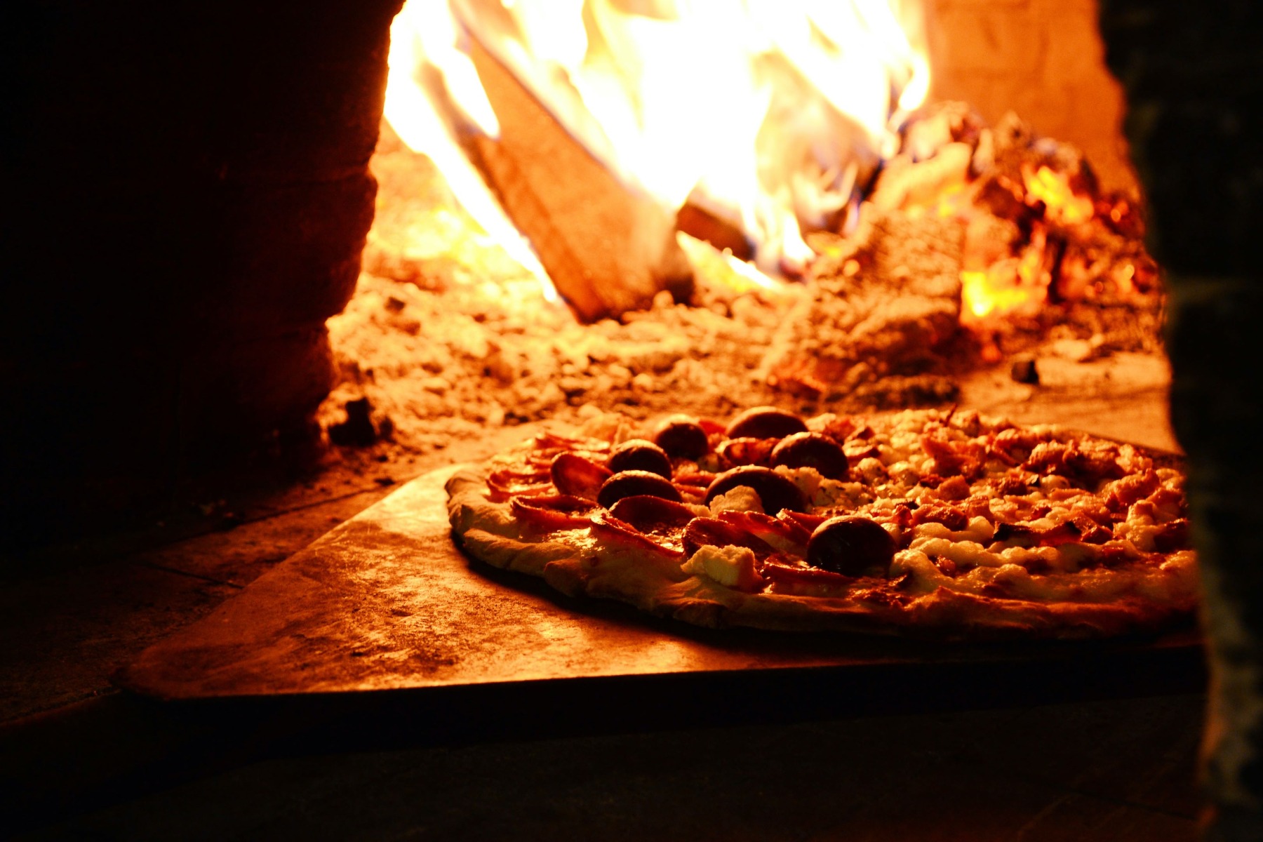 Pizza in einem holzbefeuerten Ofen backen